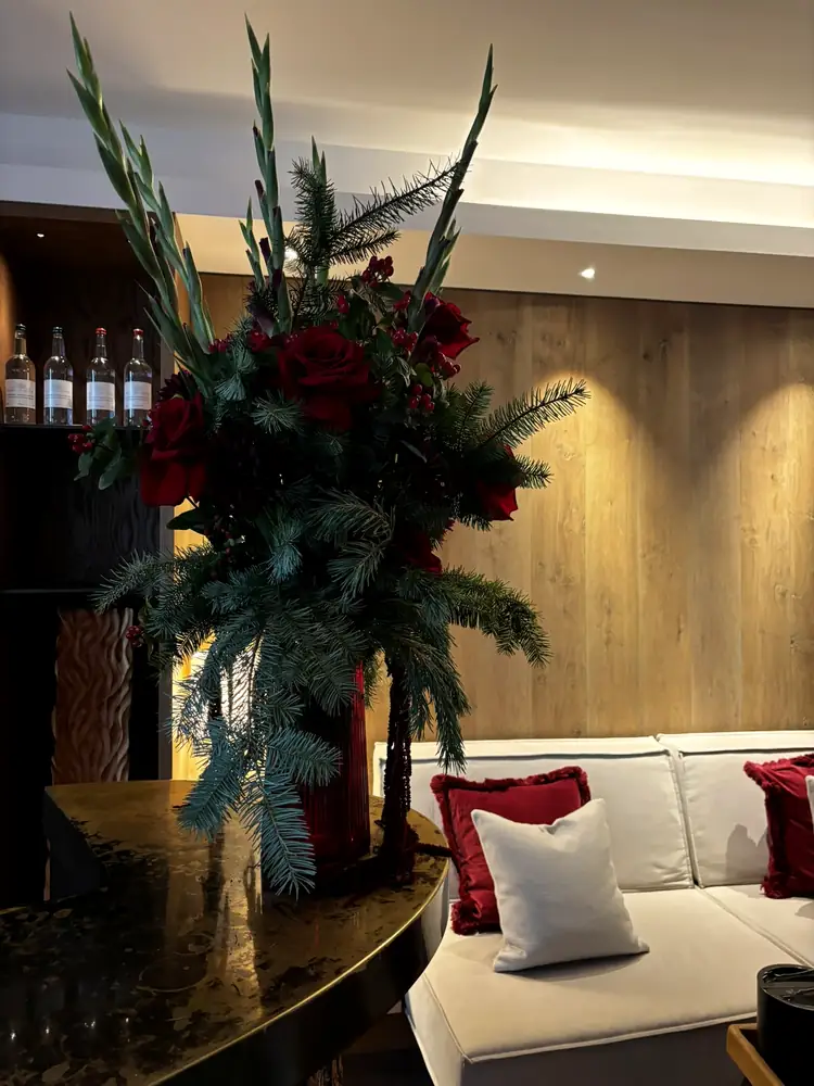 Arrangement in a claret vase beside a white sofa