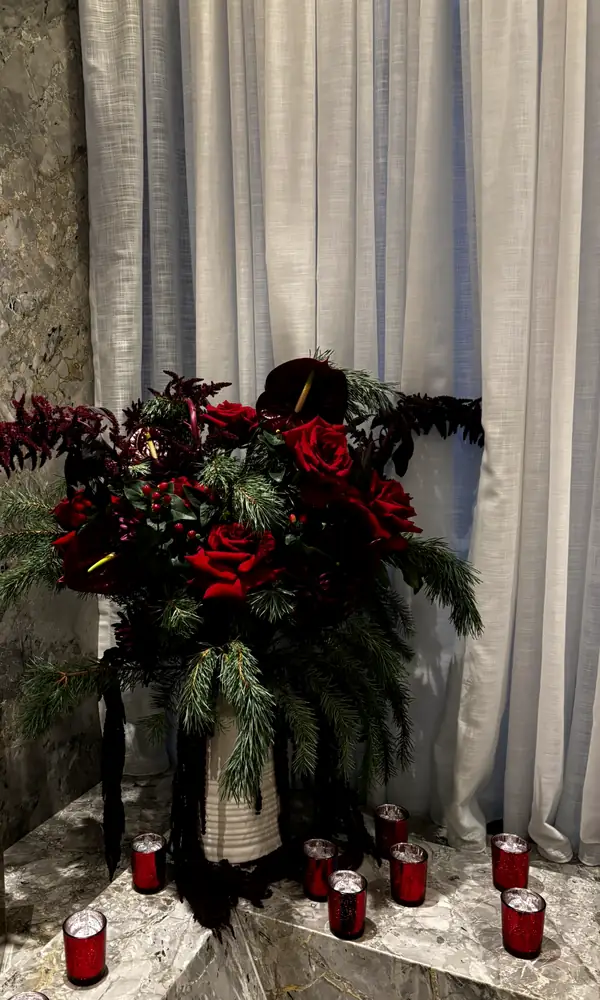 Red arrangement with candles beside a marble wall