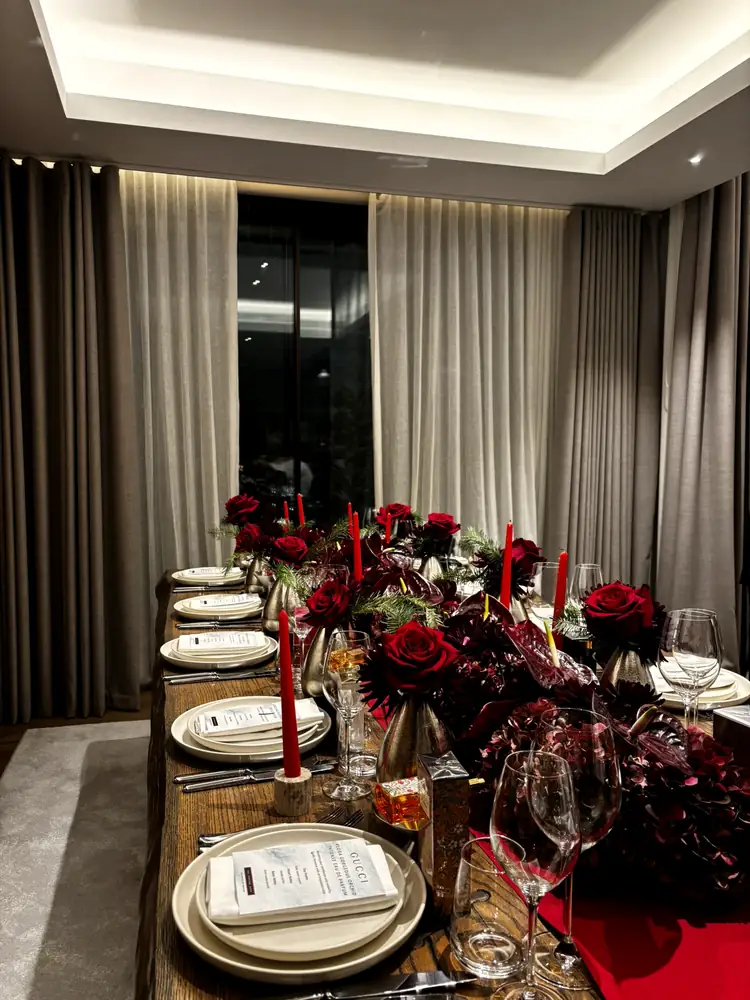 Dining room table dressed with red flowers and candles
