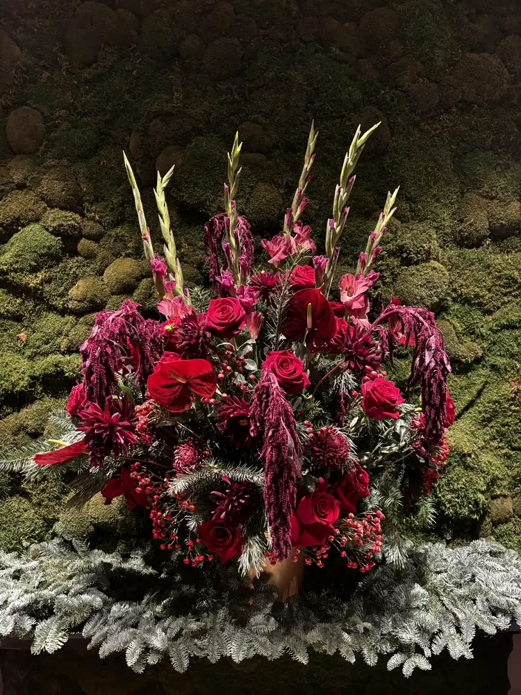 Large pedestal arrangement of roses, gladioli, dahlias and amaranthus against a living moss wall