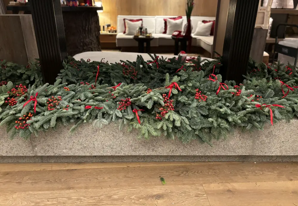 Long planter filled with fresh fir, red rosehips and red ribbon ties