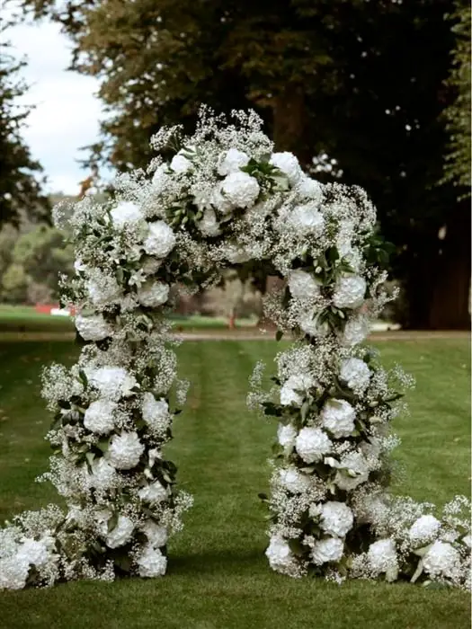White floral wedding arch on a lawn