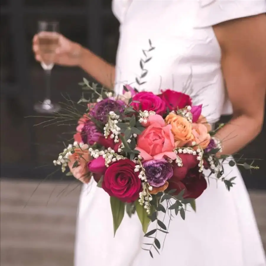 Bride holding a bright pink and red bouquet