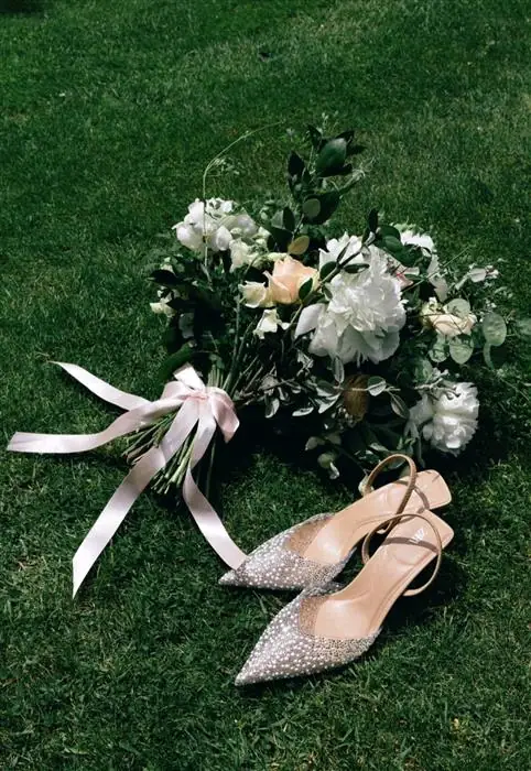 Bridal shoes beside a white bouquet
